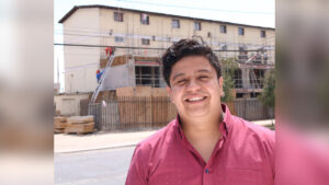 Imagen de Pavel Ayala con un edificio de blocks detrás suyo